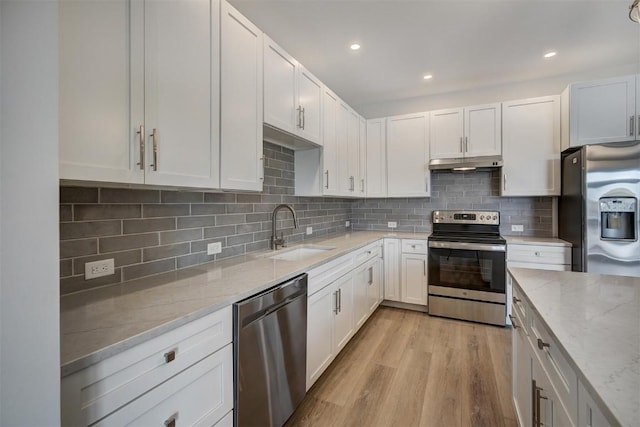 kitchen with white cabinetry, sink, stainless steel appliances, light stone counters, and light hardwood / wood-style flooring