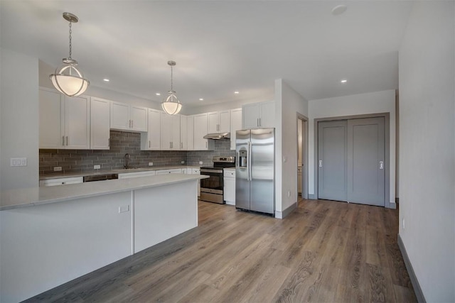 kitchen with decorative light fixtures, light hardwood / wood-style floors, white cabinetry, and appliances with stainless steel finishes