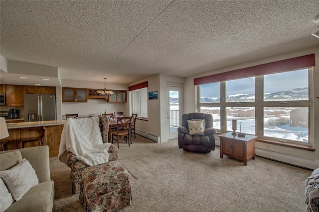 living room with a mountain view, a textured ceiling, light carpet, and a baseboard heating unit