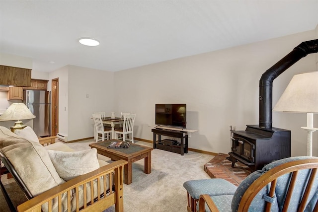 carpeted living room featuring a wood stove and a baseboard heating unit