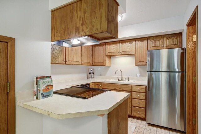 kitchen featuring ventilation hood, sink, black electric cooktop, kitchen peninsula, and stainless steel refrigerator