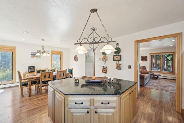 kitchen with dark stone countertops, a center island, a healthy amount of sunlight, and decorative light fixtures