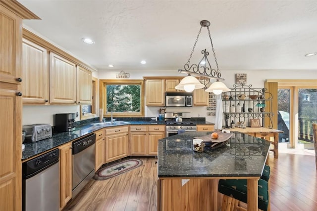 kitchen with hanging light fixtures, sink, light wood-type flooring, appliances with stainless steel finishes, and a kitchen island