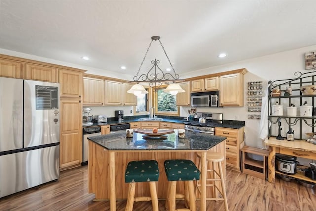 kitchen with pendant lighting, a kitchen island, sink, and appliances with stainless steel finishes