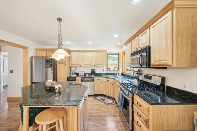 kitchen featuring light brown cabinetry, stainless steel appliances, sink, light hardwood / wood-style flooring, and hanging light fixtures