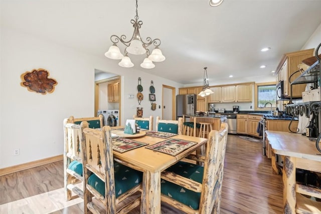 dining room with separate washer and dryer, sink, wood-type flooring, and a notable chandelier