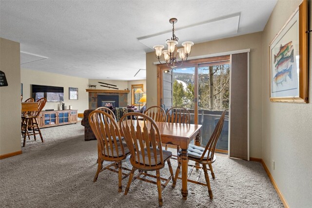 dining area with light carpet, a tiled fireplace, baseboards, and a notable chandelier