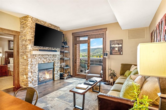 living area with visible vents, a fireplace, and wood finished floors