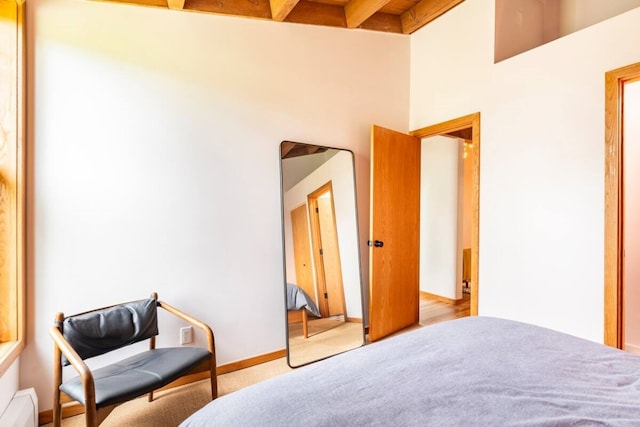 carpeted bedroom with beam ceiling and a high ceiling