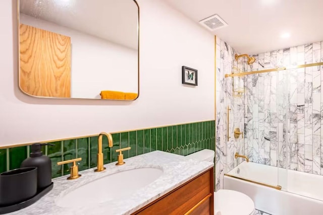 full bathroom featuring toilet, vanity, and shower / bath combination with glass door