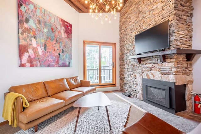 living room with a stone fireplace, a chandelier, and a towering ceiling