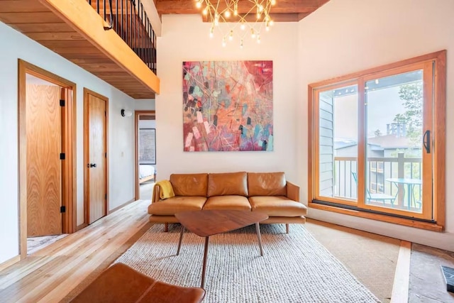 living room featuring hardwood / wood-style flooring, a notable chandelier, beamed ceiling, and a high ceiling