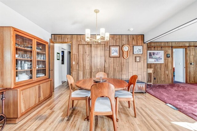 dining area with a notable chandelier and wooden walls