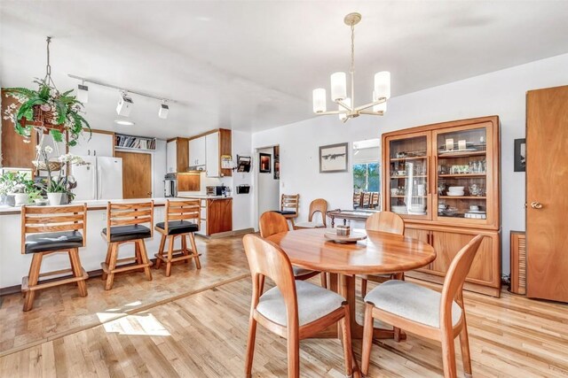 dining area featuring a chandelier, light wood-type flooring, and rail lighting