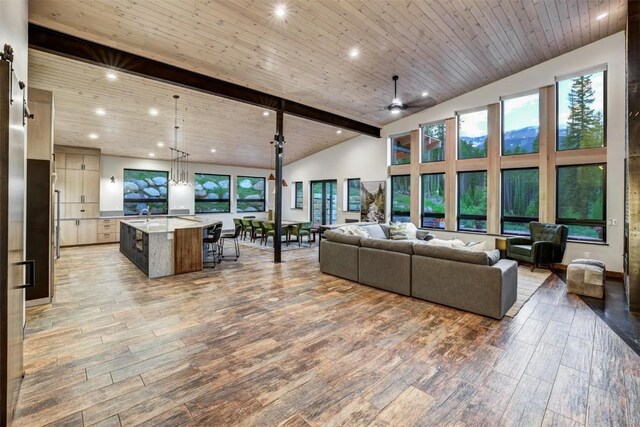 living room with beamed ceiling, ceiling fan, and high vaulted ceiling