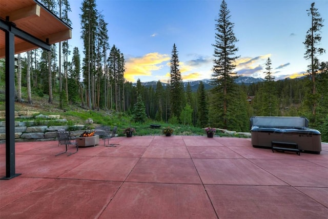 patio terrace at dusk featuring a mountain view and a hot tub