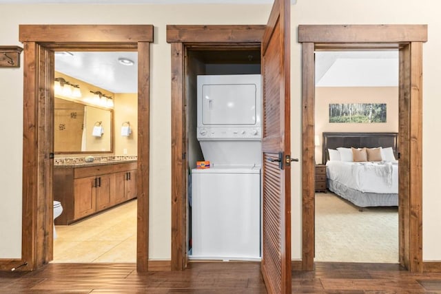 clothes washing area featuring stacked washer and dryer and hardwood / wood-style flooring