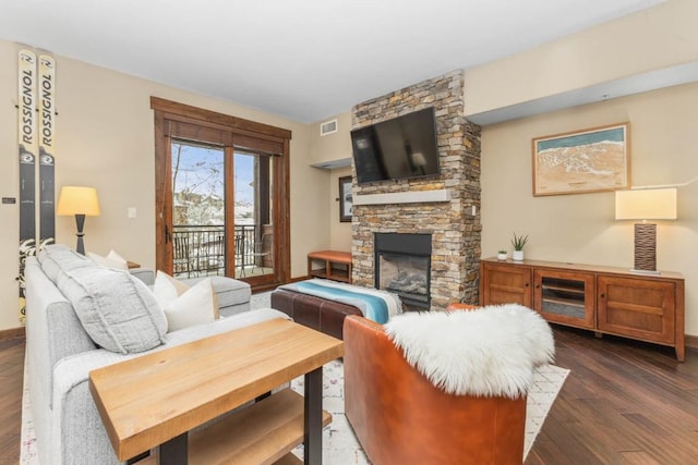 living room featuring dark wood-type flooring and a stone fireplace