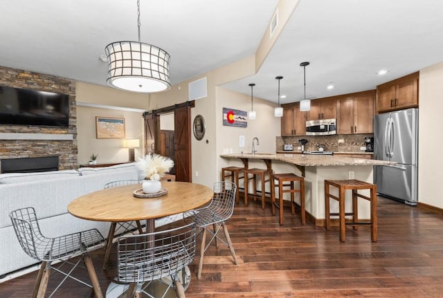 dining area with sink, dark wood-type flooring, and a barn door