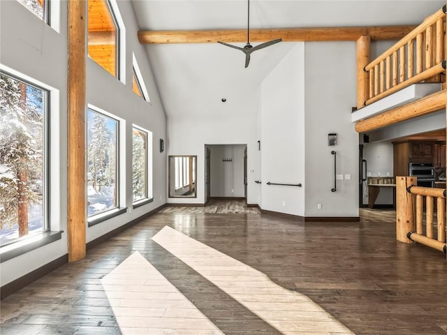 living room featuring beam ceiling, dark wood-type flooring, and a towering ceiling