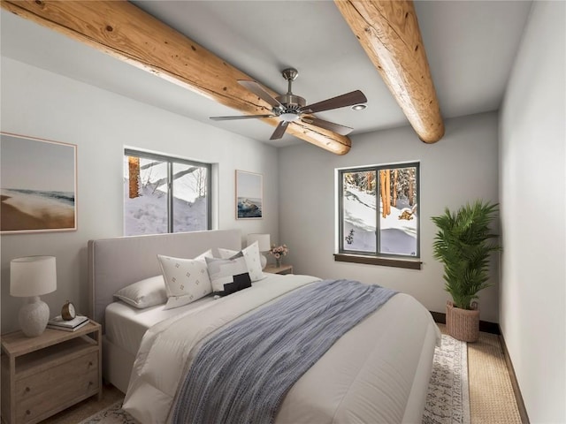 bedroom with multiple windows, ceiling fan, and beamed ceiling