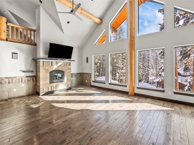 unfurnished living room featuring high vaulted ceiling, a fireplace, beamed ceiling, hardwood / wood-style flooring, and ceiling fan