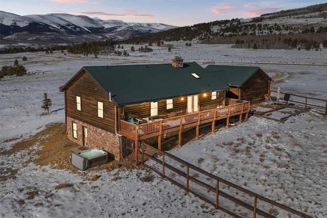 snow covered rear of property with a deck with mountain view