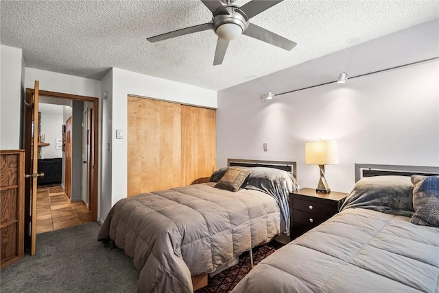 bedroom with tile patterned floors, carpet, a closet, a textured ceiling, and a ceiling fan