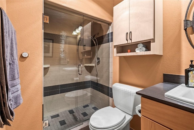 bathroom featuring a shower stall, toilet, vanity, and a textured wall