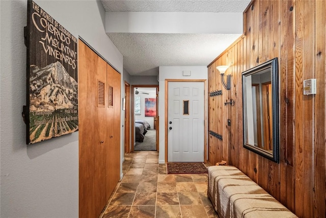 foyer with a textured ceiling and wood walls