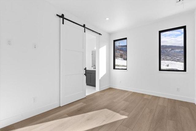 empty room with light hardwood / wood-style flooring and a barn door