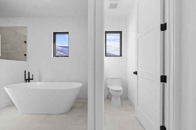 bathroom featuring plus walk in shower, plenty of natural light, and toilet