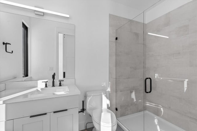 bathroom featuring vanity, a shower with shower door, and toilet