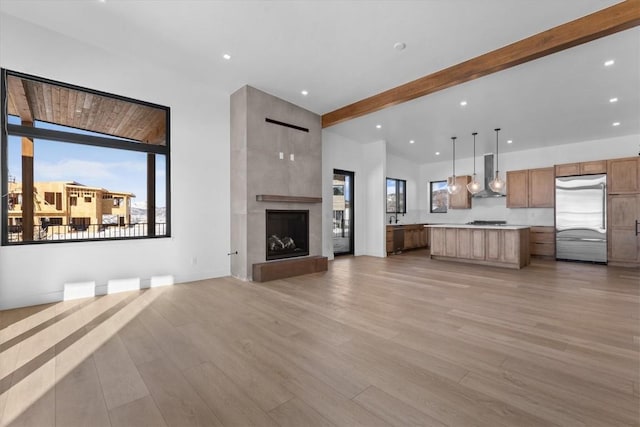 unfurnished living room with a fireplace, light hardwood / wood-style flooring, and beamed ceiling