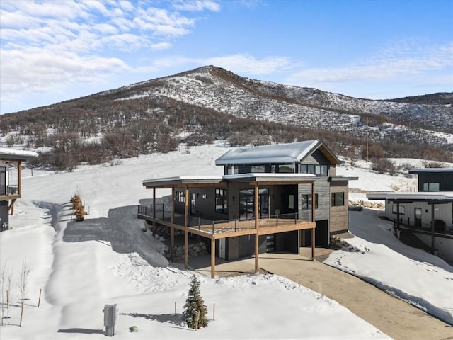 snow covered back of property featuring a deck with mountain view