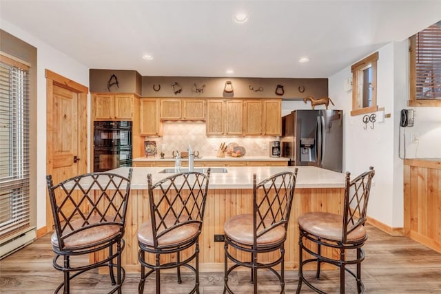 kitchen featuring light brown cabinets, backsplash, sink, double oven, and stainless steel fridge with ice dispenser