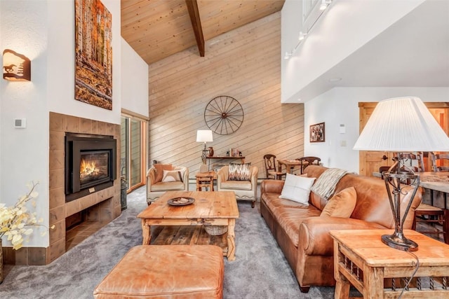 carpeted living room featuring a tile fireplace, beam ceiling, wooden ceiling, and high vaulted ceiling