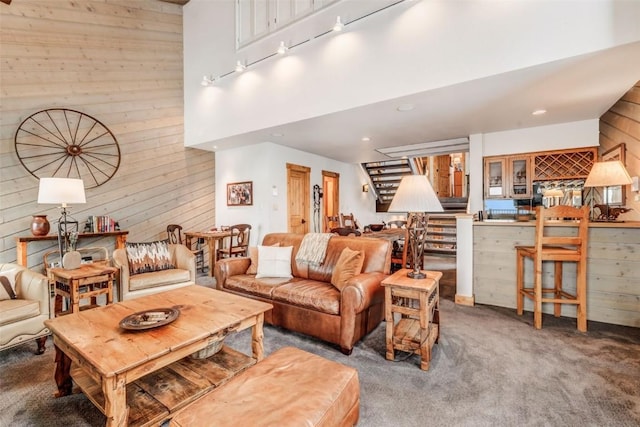 carpeted living room featuring wooden walls and a high ceiling