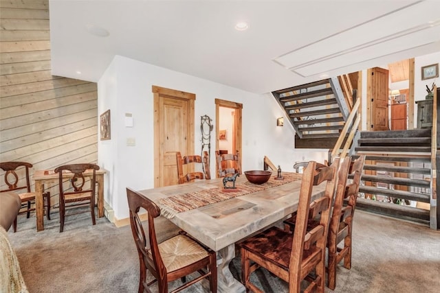 dining space with carpet and wood walls