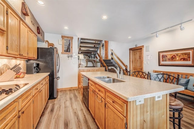 kitchen featuring sink, an island with sink, light hardwood / wood-style floors, a breakfast bar area, and appliances with stainless steel finishes