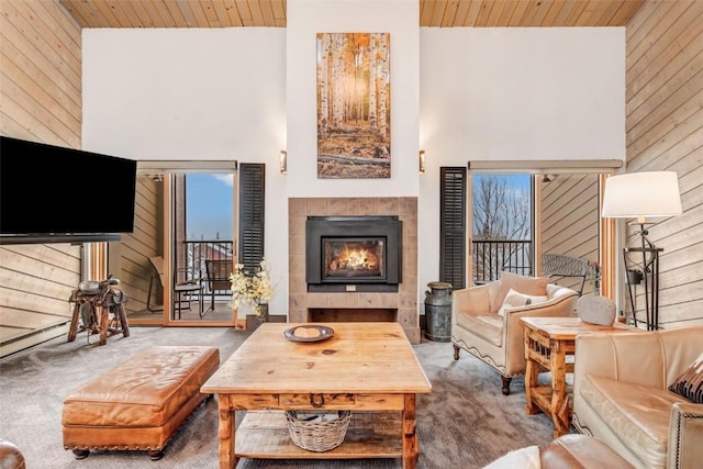 carpeted living room featuring a tile fireplace, high vaulted ceiling, and wooden ceiling