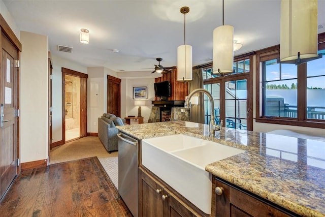 kitchen with pendant lighting, sink, stainless steel dishwasher, ceiling fan, and light stone countertops