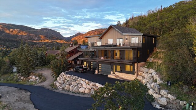 rear view of house featuring a mountain view, a balcony, and a garage