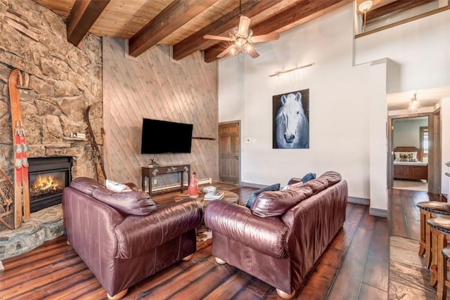 living room with beam ceiling, ceiling fan, dark wood-type flooring, a fireplace, and wood ceiling