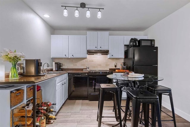 kitchen with backsplash, white cabinets, black appliances, and sink