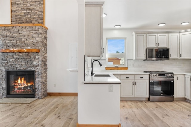 kitchen with light wood-type flooring, appliances with stainless steel finishes, backsplash, and a sink