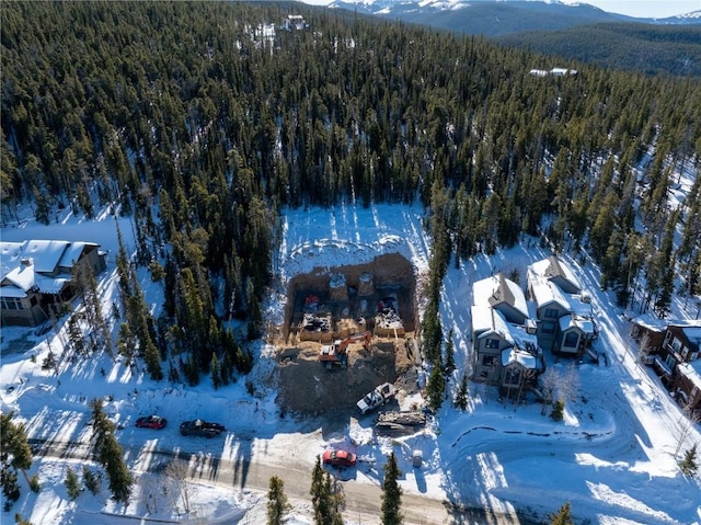 snowy aerial view featuring a mountain view and a view of trees