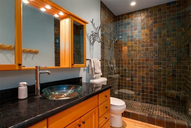 bathroom featuring a shower, vanity, hardwood / wood-style flooring, and toilet