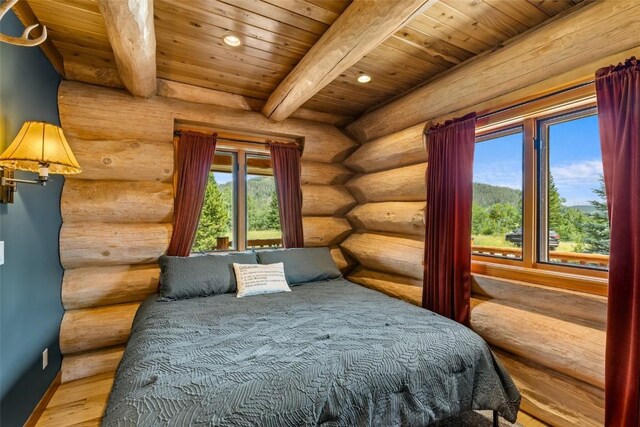 bedroom with beam ceiling, log walls, wood-type flooring, and wood ceiling