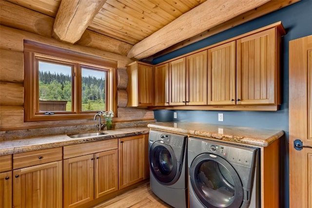 washroom with sink, log walls, wooden ceiling, cabinets, and washer and clothes dryer